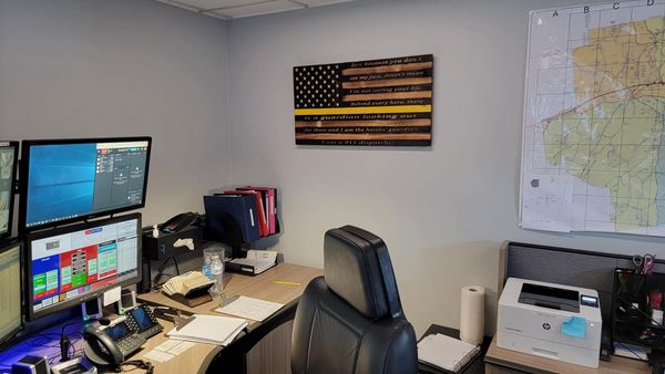 a computer with dispatch software and an American flag on the wall